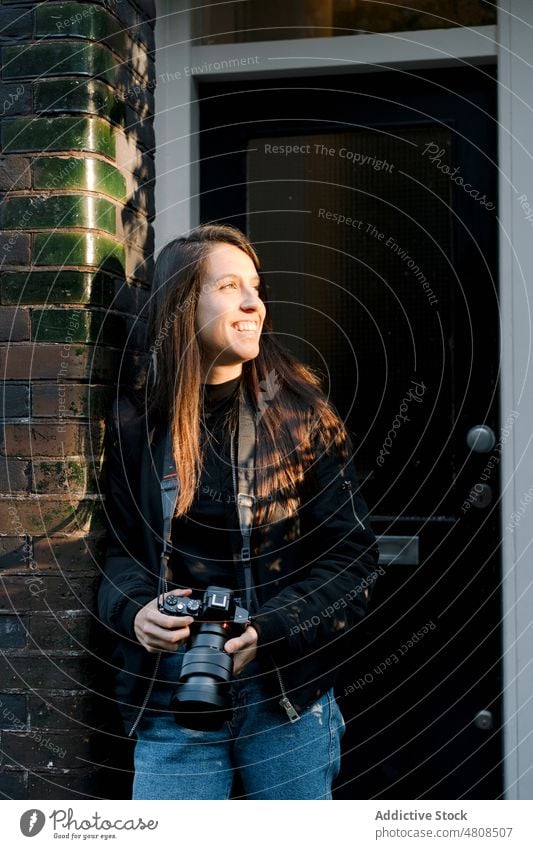 Young Hispanic female tourist checking photos on camera on street woman photo camera photographer traveler using building focus vacation photography lean on