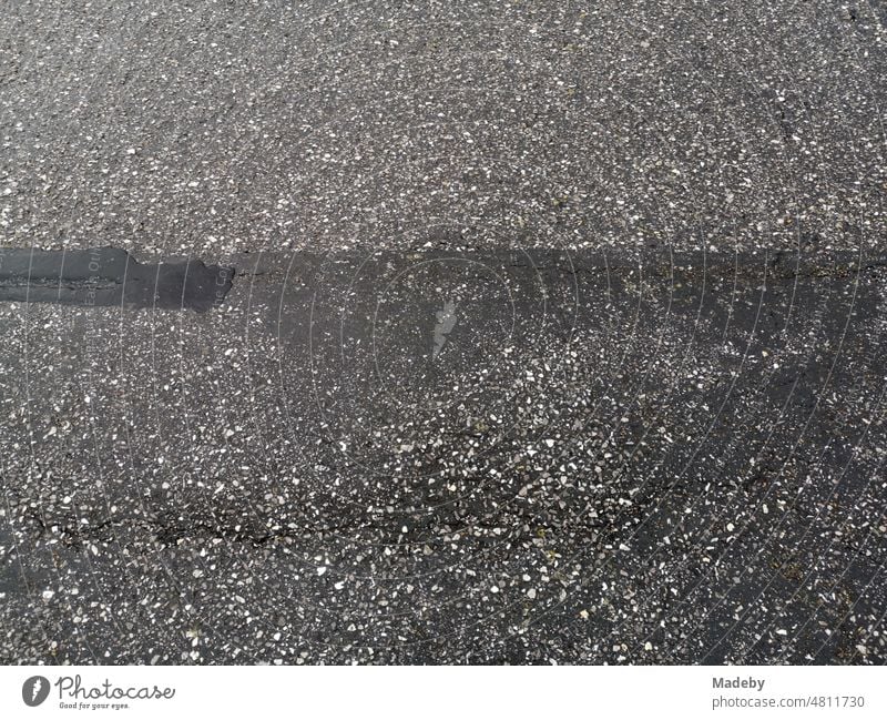 Old gray asphalt of a road on the dike at the harbor of Norddeich during rain at the North Sea in East Frisia near Norden in Lower Saxony, Germany Hiking