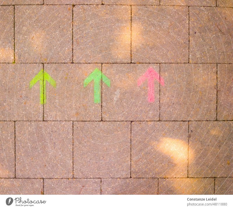 Three colorful arrows on street pavement with sunlight Street off walkway slabs Sidewalk Arrow Direction groundbreaking Signs and labeling Lanes & trails Clue