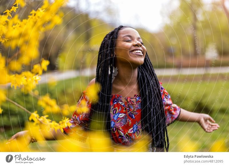 Beautiful young woman enjoying spring in the park cool carefree confident day millennials dreadlocks authentic positive real people joyful toothy smile