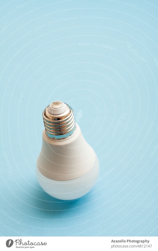 White light bulb standing upside down on blue background. downstairs Positive side Lamp Stand Paranormal Abstract surreal levitation Electric bulb Light Bulb