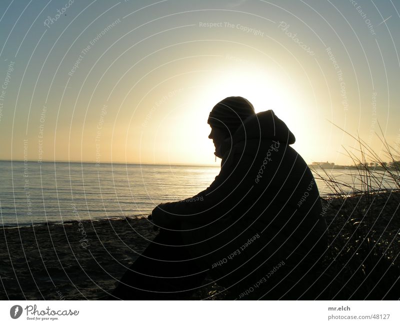 Evening at the sea Sunset Winter Back-light Ocean Lake Horizon Glistening Cold Black Silhouette silouette Contrast Sit Loneliness Looking Far-off places