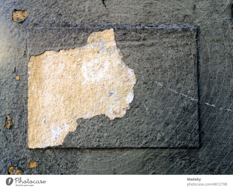 Flaking plaster reveals a new lighter layer of plaster in the sunshine at an old factory in Oerlinghausen near Bielefeld on the Hermannsweg in the Teutoburg Forest in East Westphalia-Lippe