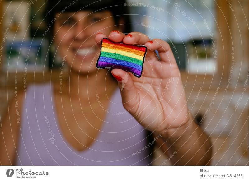 Smiling woman stretches a rainbow flag to the camera Rainbow flag pride Tolerant variety Equality Freedom LGBTQ LGBTQ+ Pride purple symbol Love Woman lesbian