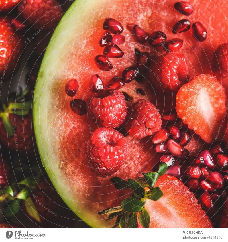 Close up of red fruits on sliced watermelon: strawberries, raspberries and pomegranate seeds. close up delicious sweet dessert summer top view health background