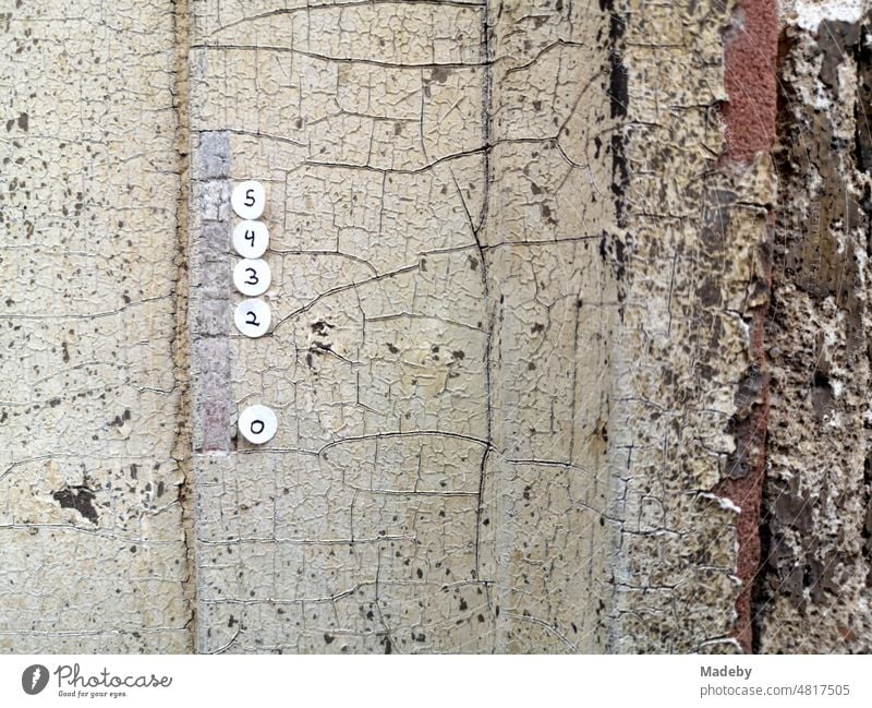 round paper sticker with handwritten numbers on the door frame of an old empty house in the district of Sachsenhausen in Frankfurt am Main in Hesse, Germany