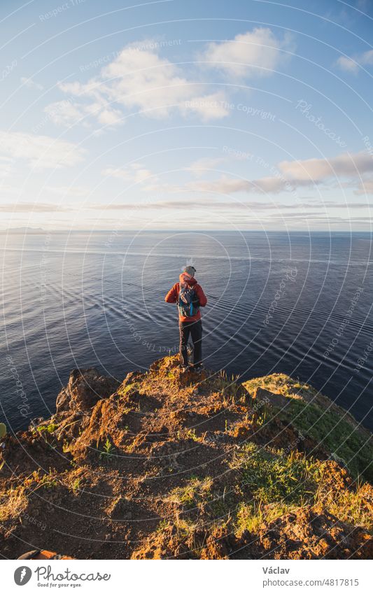 Passionate backpacker at 24 years old stands on the edge of a cliff in a place called Cristo Rei, Camara de Lomos, Madeira, belonging to Portugal. Sunrise on the Atlantic coast