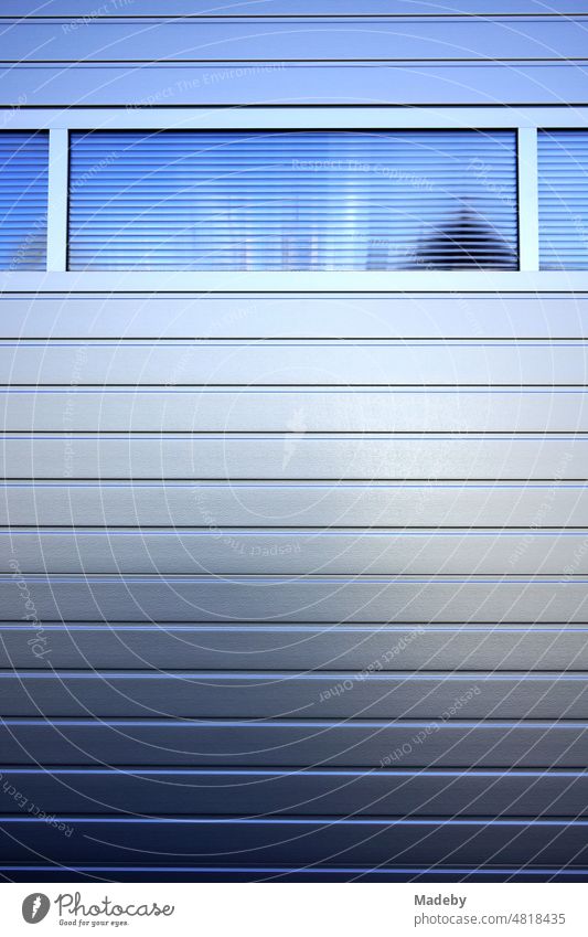 Blue shimmering professional modern rolling door and segment door on a garage in Wettenberg Krofdorf-Gleiberg near Giessen in Hesse, Germany Goal Garage