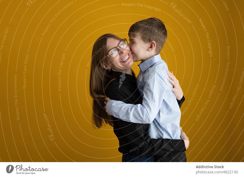 Loving mother hugging happy son kiss love smile home together relationship portrait woman boy smart casual bright glasses positive optimist glad fondness