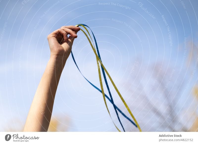 Faceless lady holding ribbons with Ukrainian flag under blue sky woman ukrainian peace demonstrate nature patriot freedom yellow color show countryside culture