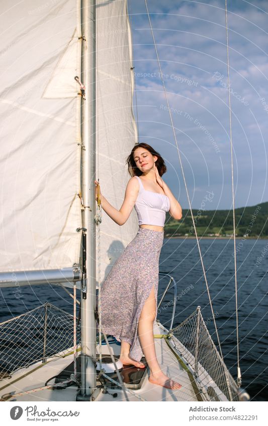 Calm young lady admiring nature while standing on sailboat woman sea yacht admire holiday cruise summer vacation female portrait trendy style trip brown hair