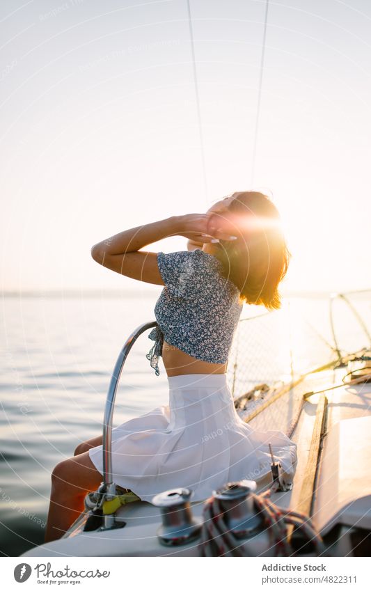 Stylish female tourist resting on yacht and admiring sunset over sea woman admire sailboat traveler vacation cruise holiday style portrait trendy trip young