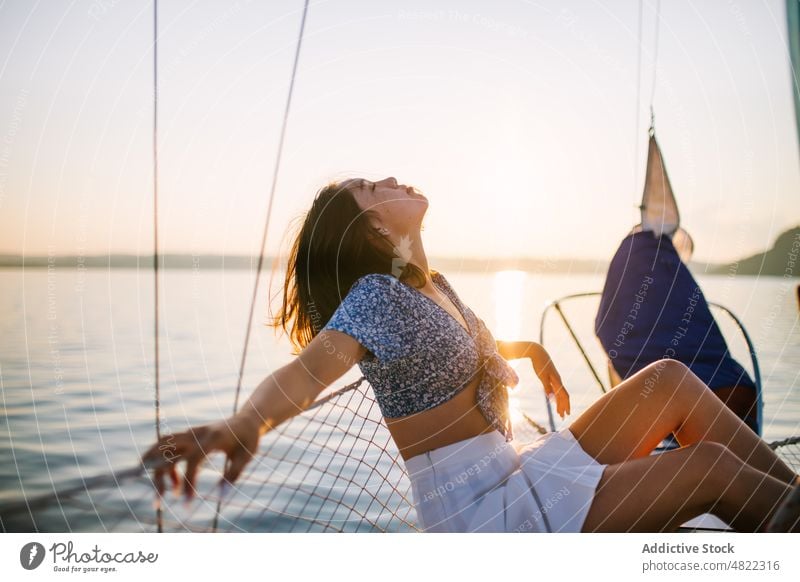 Stylish female tourist resting on yacht while closed eyes woman sea sailboat traveler sunset vacation cruise holiday style trendy trip young brunette sundown