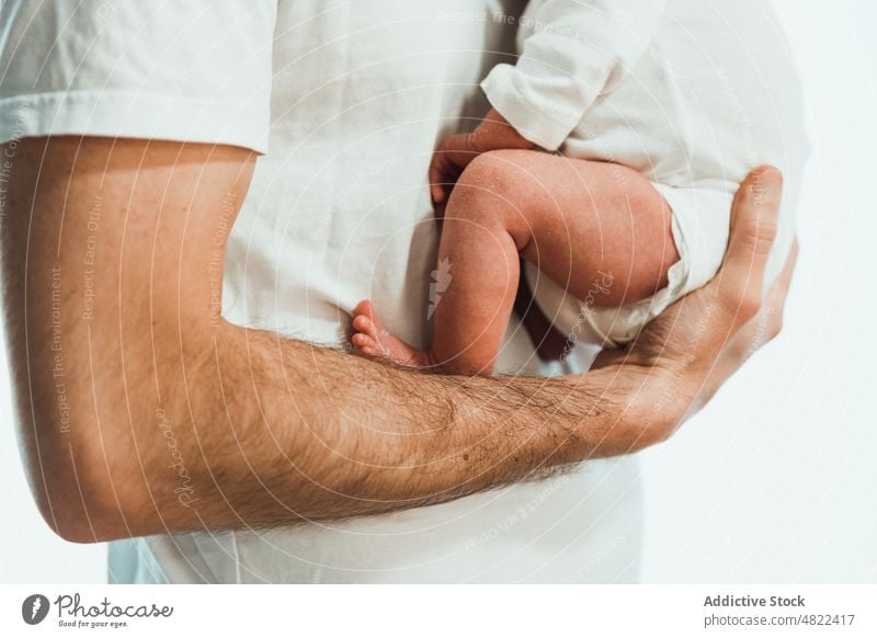 Crop unrecognizable father hugging cute baby against white background man embrace love newborn adorable childcare together innocent babyhood male young infant