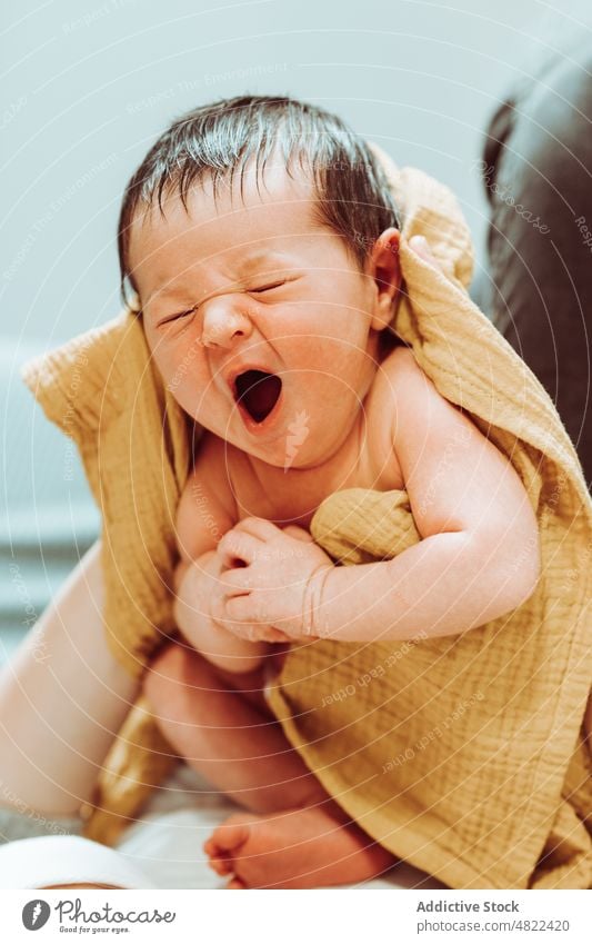 Crop mother cuddling cute newborn yawning with closed eyes baby woman motherhood babyhood innocent maternal love embrace towel adorable tender mom female casual