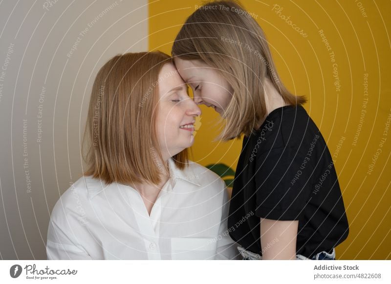 Happy kid with young mother touching foreheads with closed eyes woman child touch forehead smile eyes closed happy daughter love together bonding home