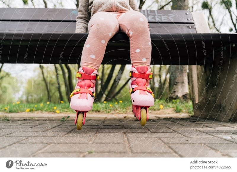 Anonymous cute child in roller skates relaxing on bench in park rest girl active hobby adorable activity kid casual leisure childhood carefree path nature