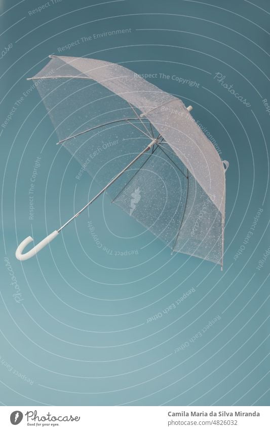 Transparent umbrella on blue background. Photo in studio. accessory autumn climate concept fall fashion fresh hand liquid protection rain raindrop rainy