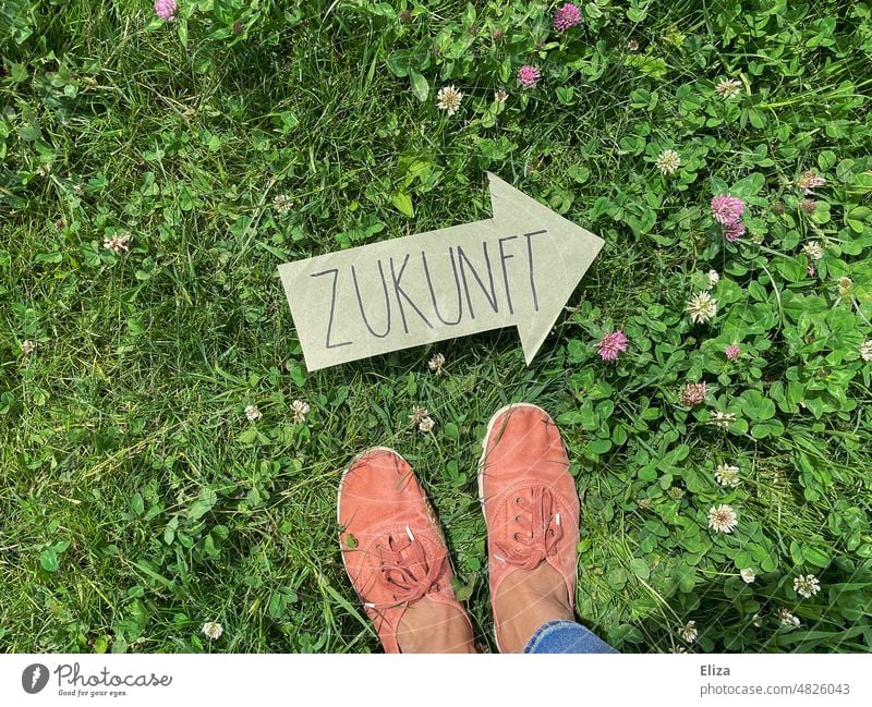 Person stands on a meadow in front of a green arrow on which is written the word future Future Arrow Forward-looking Direction Green authored sustainability