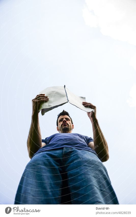 Man reading from a booklet Booklet Reading Meditative overlearn ponder understand Worm's-eye view especially Concentrate out