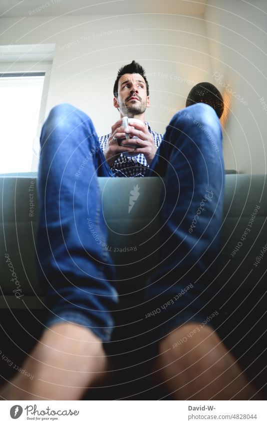 Man sits on the sofa with a cup in his hands and thinks Meditative Think thoughts Emotions Fear of the future uncertainty Fears Poverty Sadness