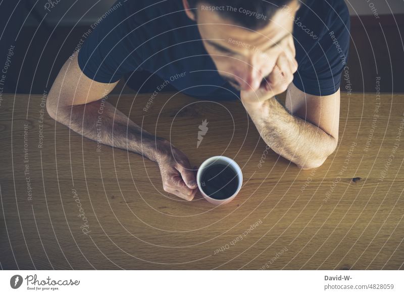 Man sitting at table with cup of coffee in hand Coffee Cup Table Sit Wait bored Exasperated Coffee mug Coffee break Meditative thoughts Worries