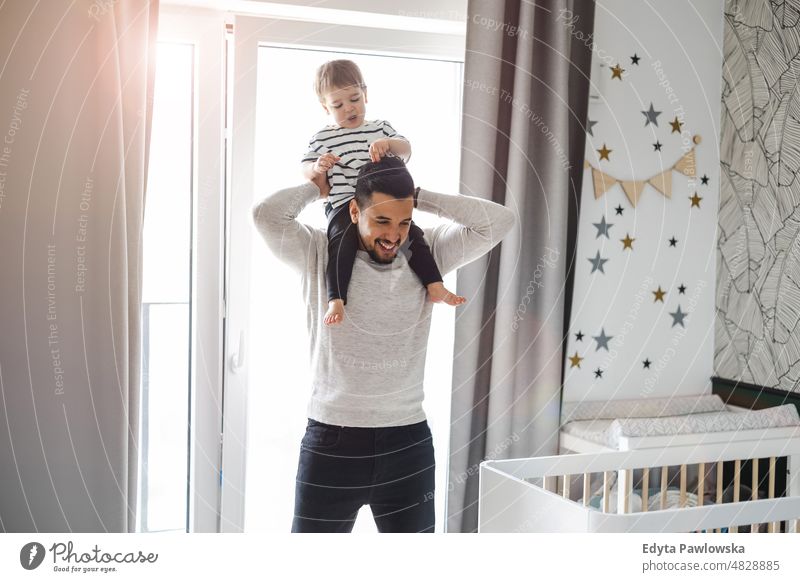 Dad playing with his little son at home adult affection baby bonding boy candid care child childhood domestic enjoying family fun happiness happy house indoors