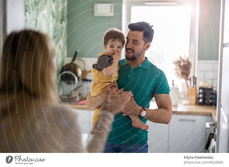 Young parents playing with their child at home weekend playful mom mother father domestic positive leisure enjoying adult affection baby bonding boy candid care