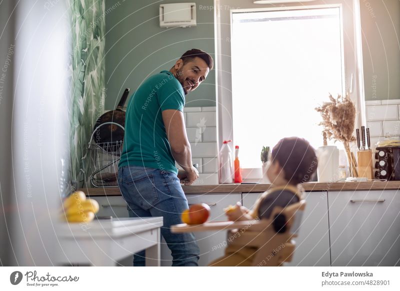 Father with his young child in the home kitchen adult affection baby bonding boy candid care childhood domestic enjoying family fun happiness happy house