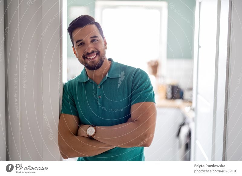 Smiling man standing in the doorway to the kitchen candid natural real people looking at camera crossed arms relax success laughing face healthy fun positive