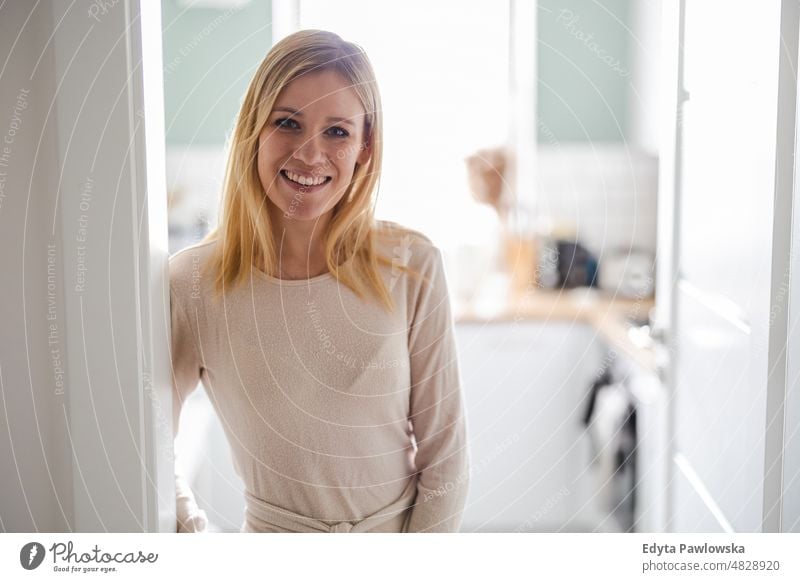 Smiling young woman standing in the kitchen looking at camera toothy smile blond beauty healthy morning mother professional casual indoors confidence confident