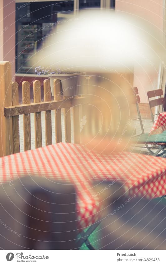 Beer garden detail shot with red and white check table cloth, wooden fence in background and blurred lamp in foreground r Table tablecloth Outdoor tablecloths