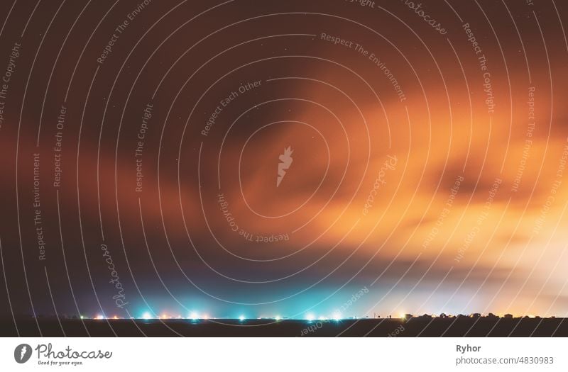 Night Sky With Rare Glowing Stars Shining Through The Cloudiness Overcast Above Countryside Town Landscape. Rural Field Meadow In Early Spring Starry backdrop