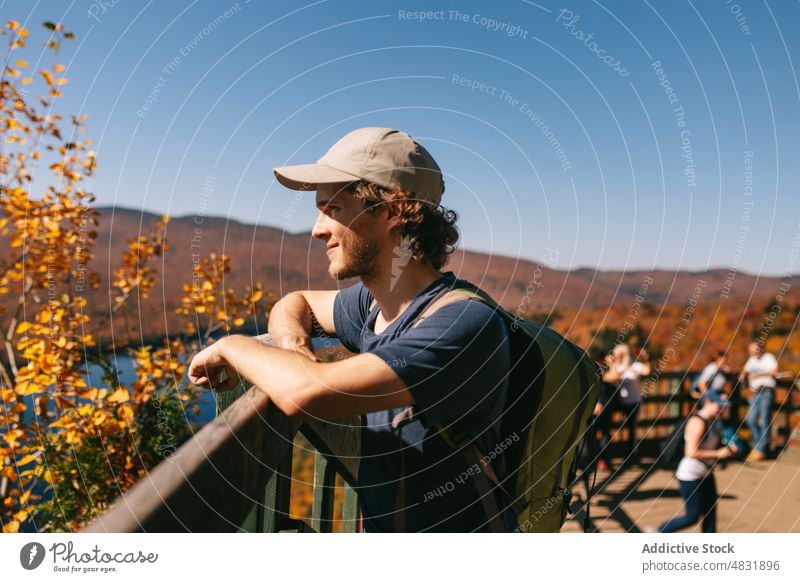 Male traveler standing on wooden footbridge in mountainous valley man forest tranquil walkway sightseeing autumn tourist woods male natural landscape fall