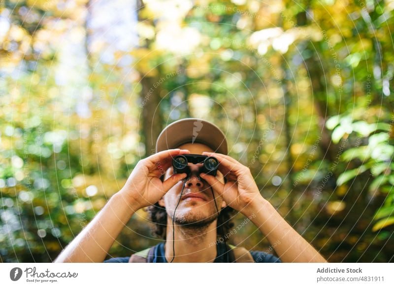 Hiker observing forest in binoculars man traveler observe admire trekking adventure explore male highland nature hike hiker hill woodland sit curious backpack