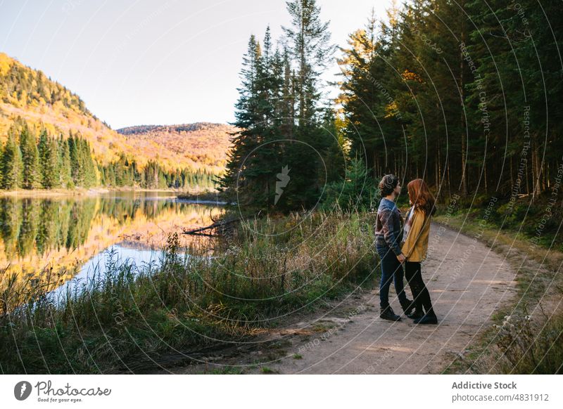 Loving couple cuddling on lake shore on autumn day embrace forest trip love admire hug travel relationship romantic landscape nature lakeside boyfriend