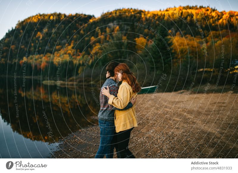 Loving couple cuddling on lake shore on autumn day embrace forest trip love admire hug travel relationship romantic landscape nature lakeside boyfriend