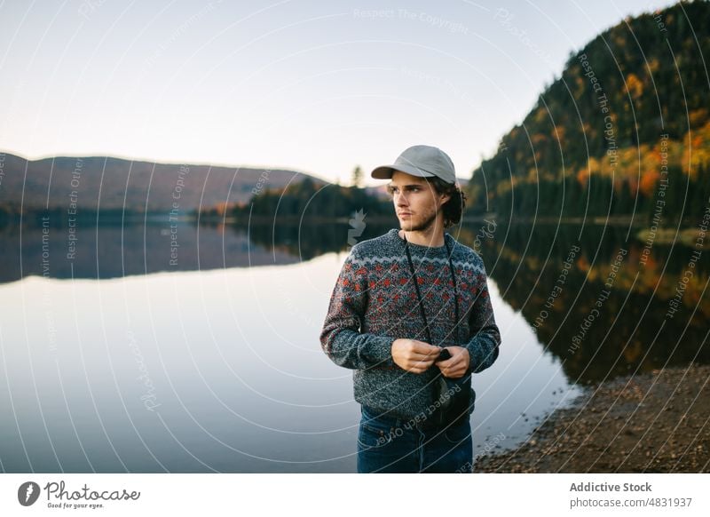 Young guy on lake shore in autumn forest at sunset man traveler wanderlust nature landscape trip tree male young scenic holiday hat mountain highland canada