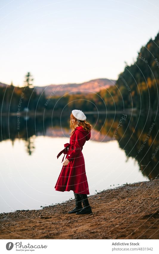 Female tourist admiring lush autumn trees surrounding lake in nature woman admire landscape wanderlust traveler forest beret trip explore canada female