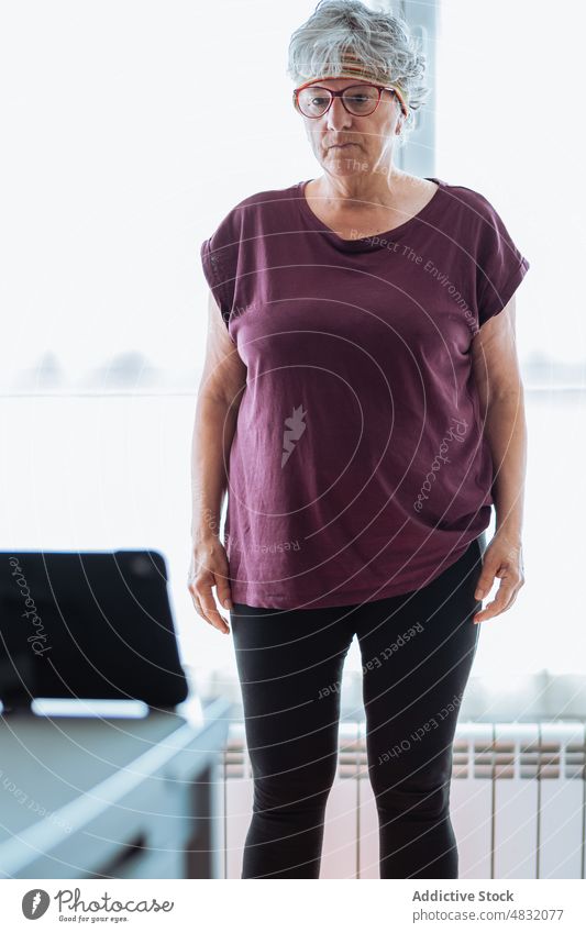 Aged female exercising at home woman exercise morning fitness training gymnastic portrait senior aged elderly pensioner hair band sportswear short hair