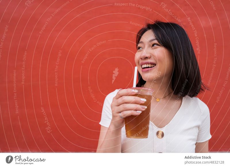 Young ethnic lady drinking takeaway refreshing beverage on street woman coffee refreshment portrait to go confident style straw female young asian brunette