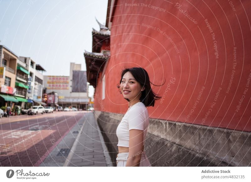 Young ethnic woman smiling at camera against red wall smile cheerful self assured personality positive portrait happy charismatic glad optimist confident female