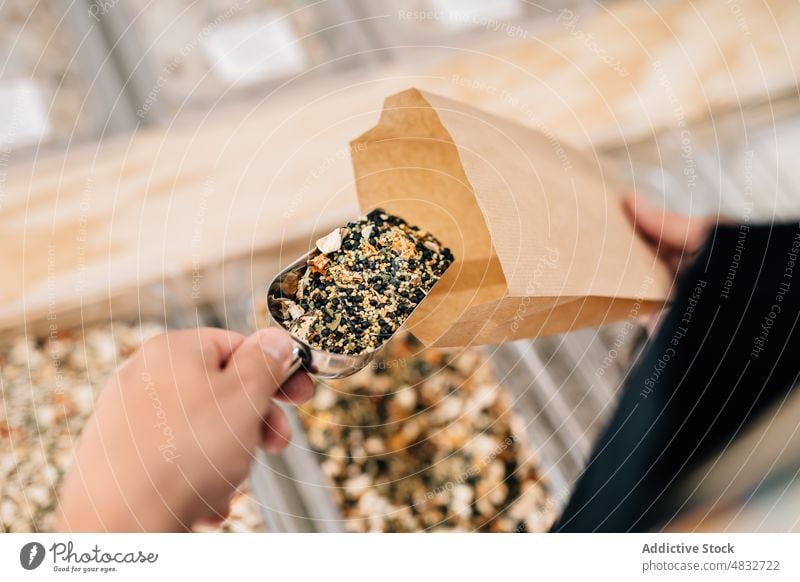 Person putting spices inside paper bag woman store dry local seasoning customer hand ingredients glass scoop consume buyer purchase female shovel natural shop