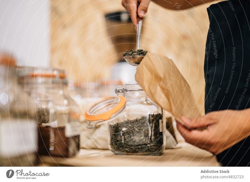 Person putting spices inside paper bag woman store dry local seasoning customer hand ingredients glass scoop consume buyer purchase female shovel natural shop