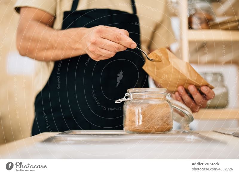 Person putting spices inside paper bag woman store dry local seasoning customer hand ingredients glass scoop consume buyer purchase female shovel natural shop