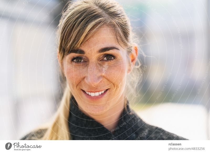 Portrait of happy student woman  looking at camera. Successful proud woman in city street at spring. Satisfied european student woman in casual clothing smiling outdoors.