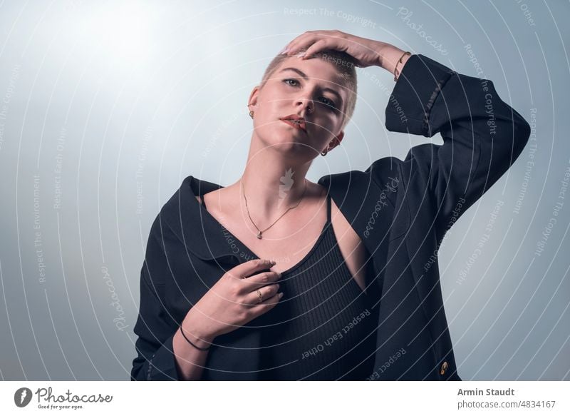 studio portrait of a young woman who thoughtfully touches her head confident passion short hair business smile lucky laugh piercing jewelry blonde female