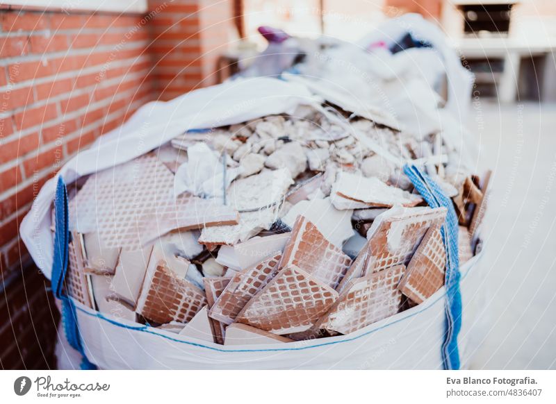 debris in bag at home construction site. Home renovation rubble demolition nobody ladder wall bricks ear defenders protection helmet real state works