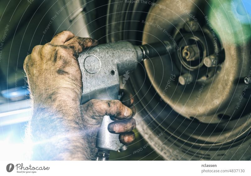 Auto mechanic changing a car tire in mechanics garage and using a electric drill to loosen the bolts. Repair service. authentic close-up shot engine automotive