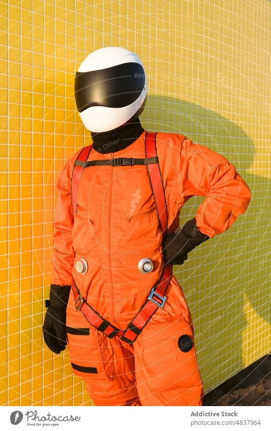 Confident cosmonaut against yellow wall astronaut spacesuit confident success costume concept sand beach explore uniform helmet brave safety spaceman aspiration